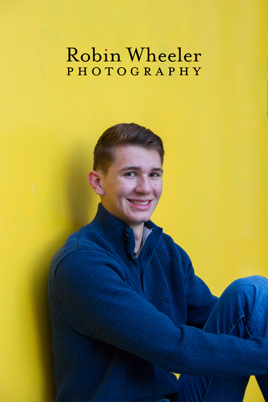 Senior photo of a boy sitting in front of a yellow door, Ontario, Oregon