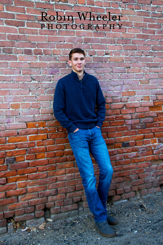 Photo of a high school senior guy leaning against a brick wall, Ontario, Oregon