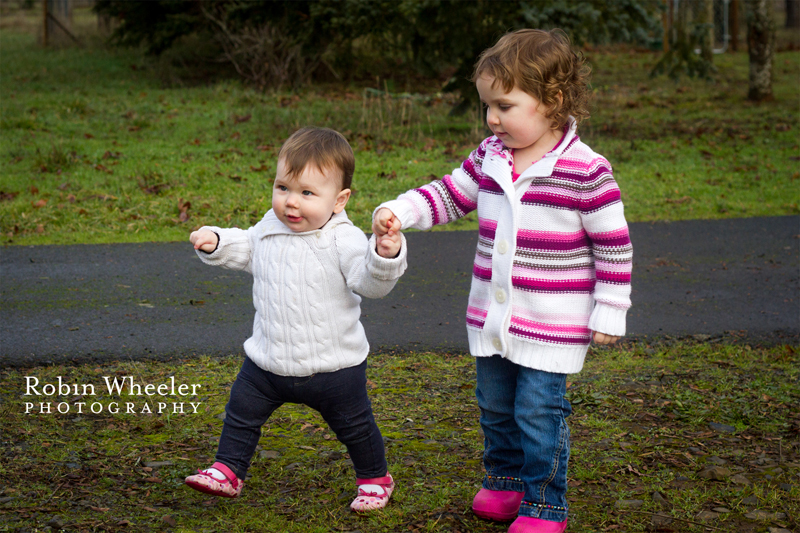 Toddler helping her baby sister walk, Dallas, Oregon