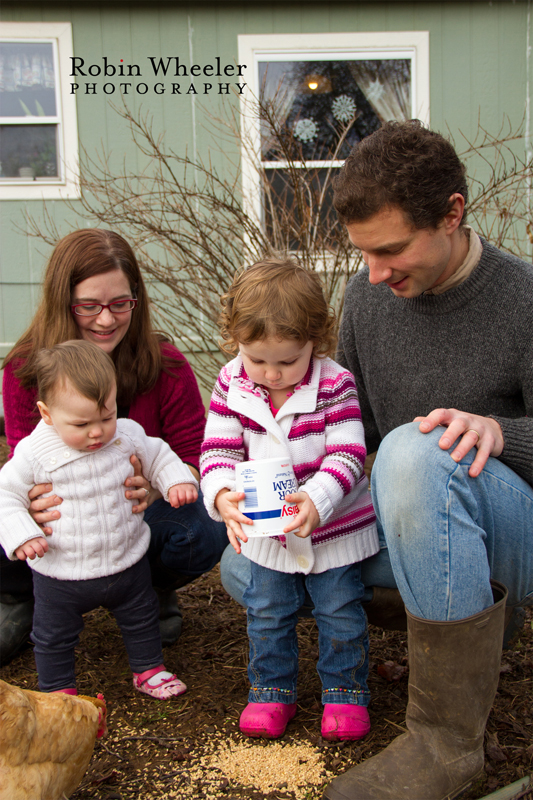 Family watching toddler dump chicken feed on the ground, Dallas, Oregon