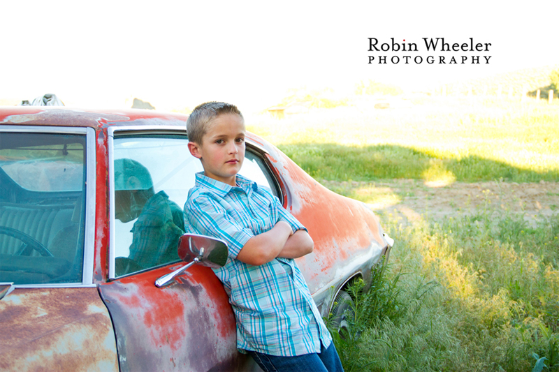 Boy leaning against an old car, Payette, Idaho