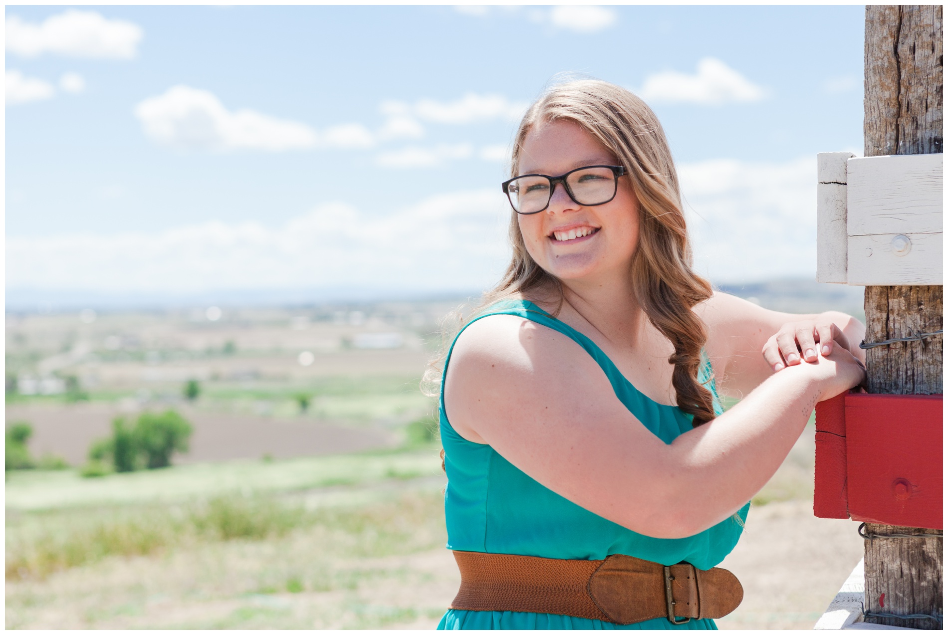 Senior picture of a girl leaning against a fence, overlooking Ontario, Oregon.