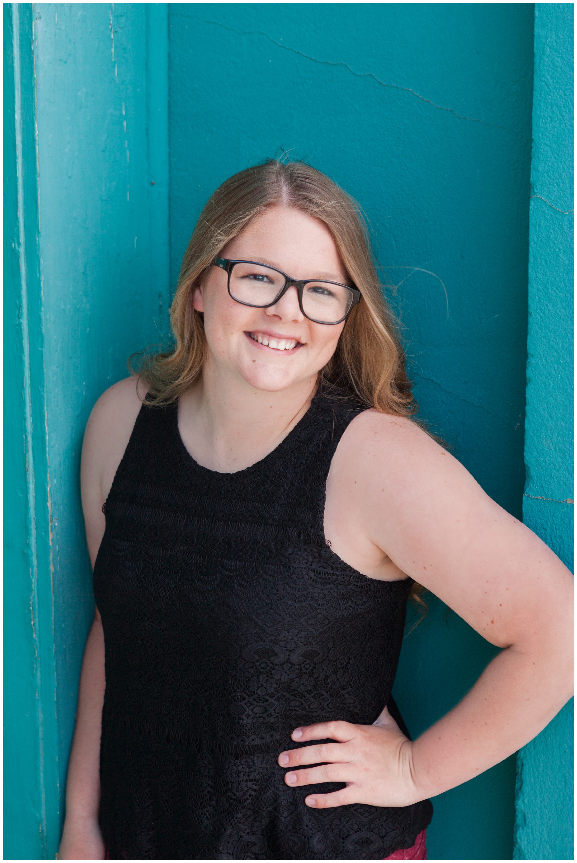 Senior photo of a girl in front of a turquoise building in Payette, Idaho.