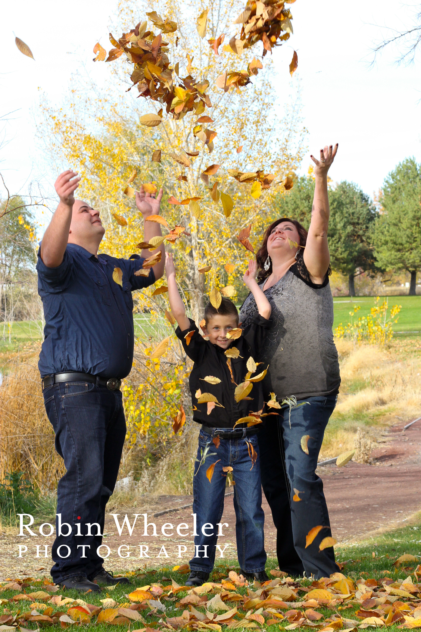 family tossing autumn leaves