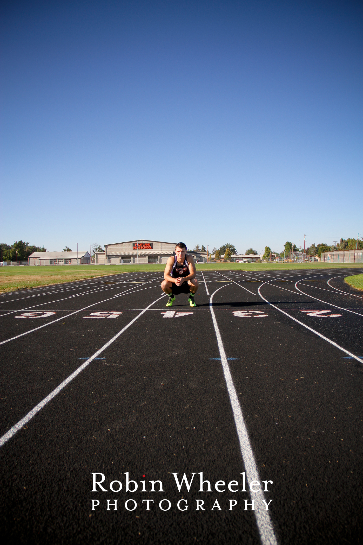 Senior guy in track uniform squats near the starting line