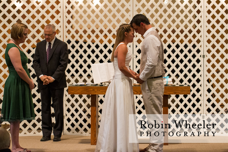 Maid of honor, minister, bride, and groom praying during the wedding ceremony, Ontario, Oregon