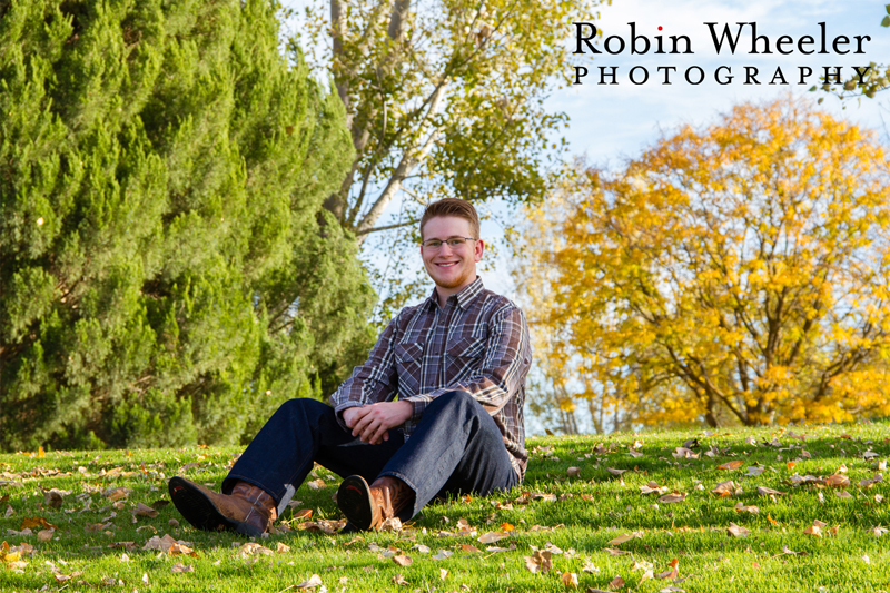 Photo of a high school senior sitting in the grass and autumn leaves in Beck-Kiwanis Park in Ontario, Oregon