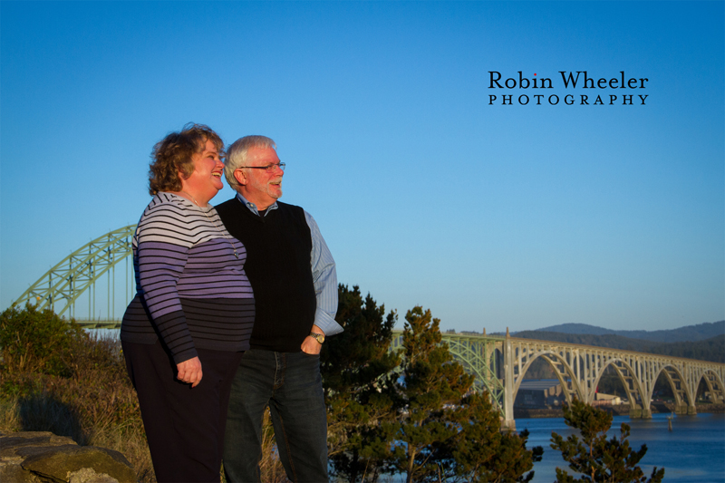 Portrait of a couple at Yaquina Bay State Recreation Site with the Yaquina Bay Bridge behind them, Newport, Oregon