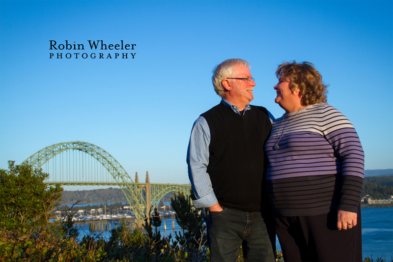 Portrait of a couple at Yaquina Bay State Recreation Site with the Yaquina Bay Bridge behind them, Newport, Oregon