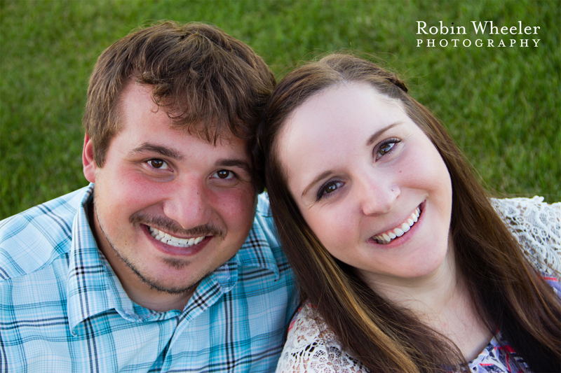 Engaged couple sitting in the grass