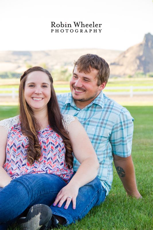 Man and woman sitting together in the grass with Malheur Butte in the background