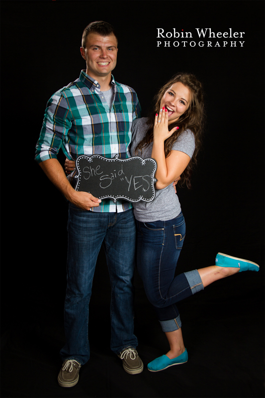 young man and young woman holding a sign that says, "She said yes!"