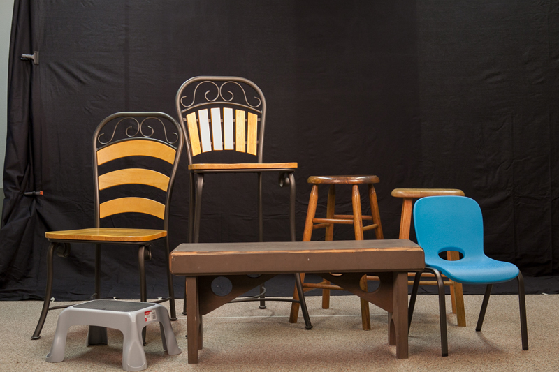 variety of chairs and stools in front of a photography backdrop