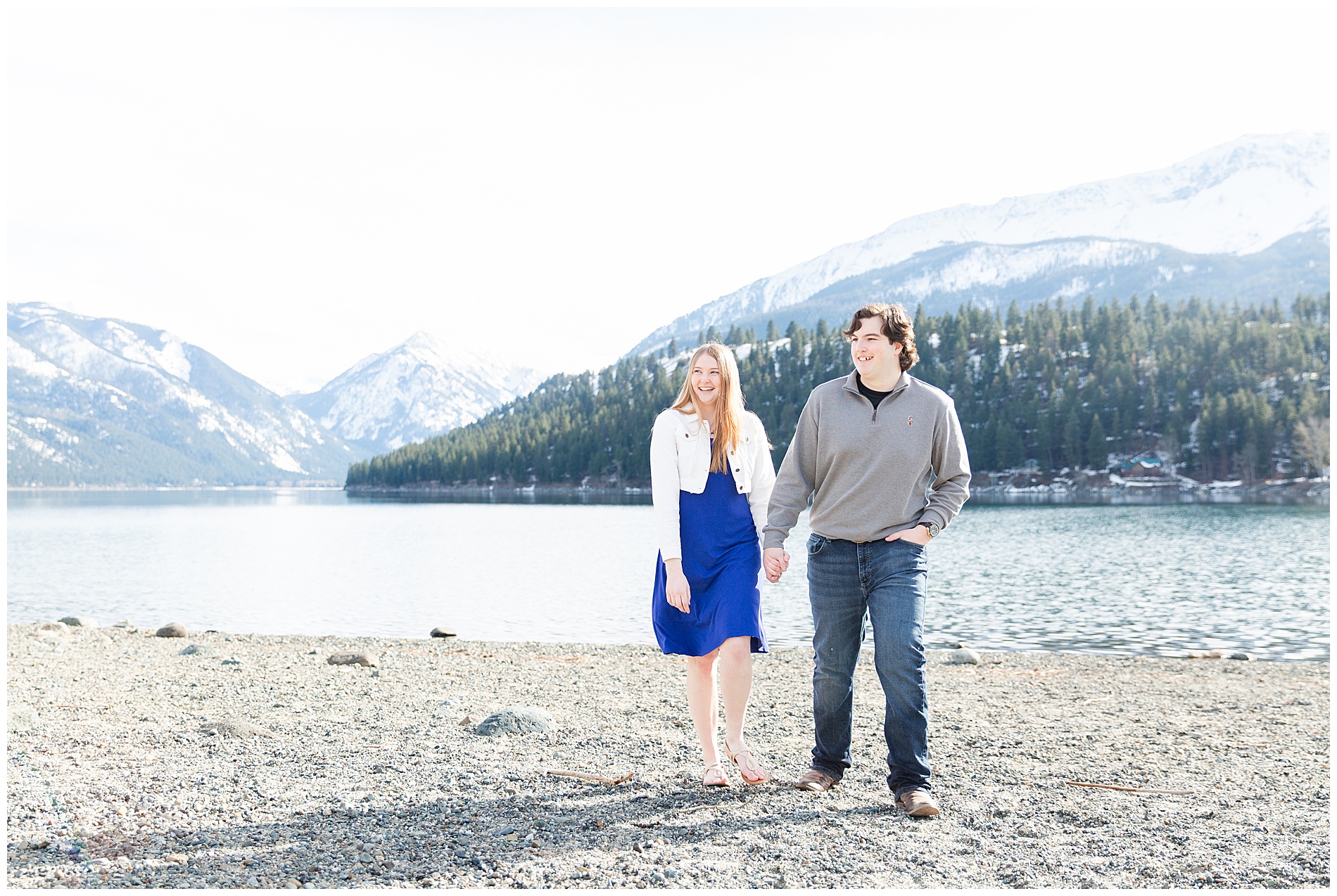 Couple walking on the shore of Wallowa Lake with the mountains behind them