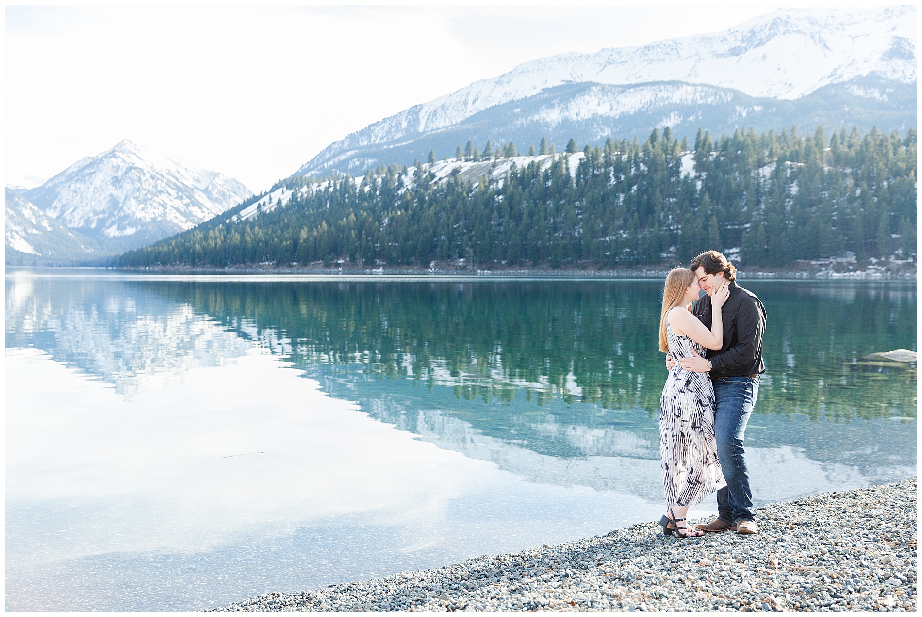 Couple standing on the shore of Wallowa Lake with the mountains reflected in the water behind them