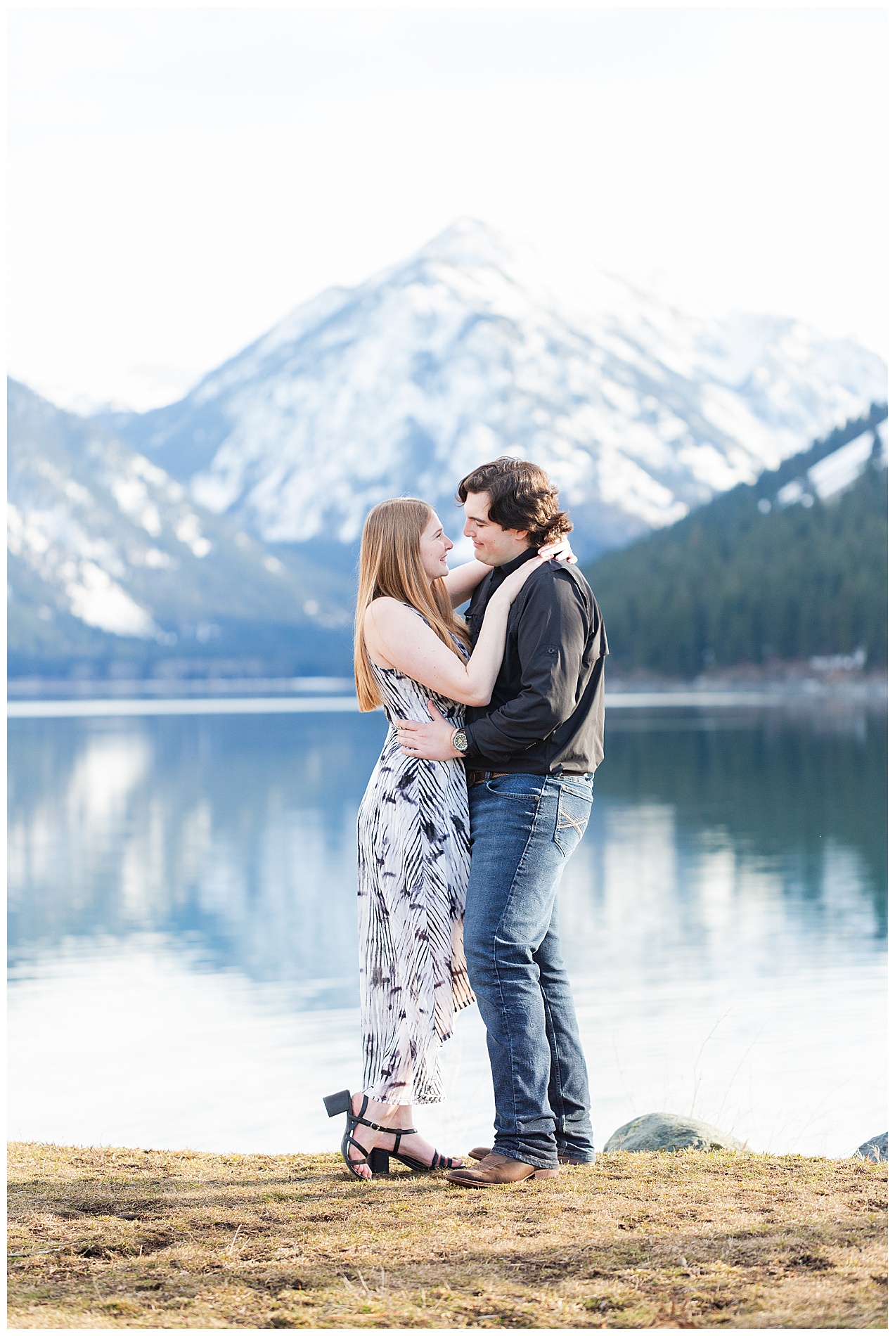 Snow-capped mountains reflected in the water behind the couple at Wallowa Lake Park