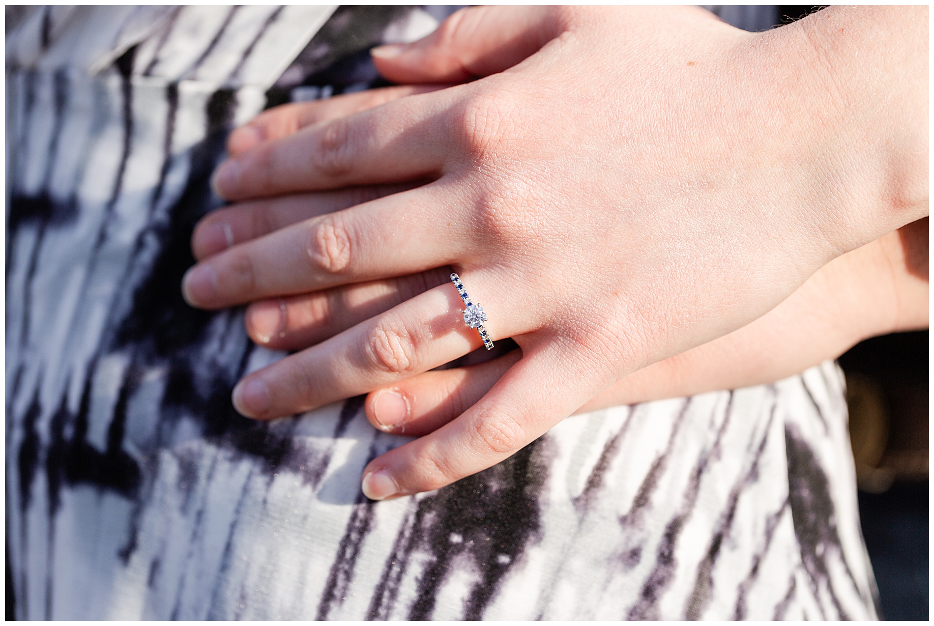 The couple's hands together, showing off the bride-to-be's engagement ring and its blue diamonds in the band