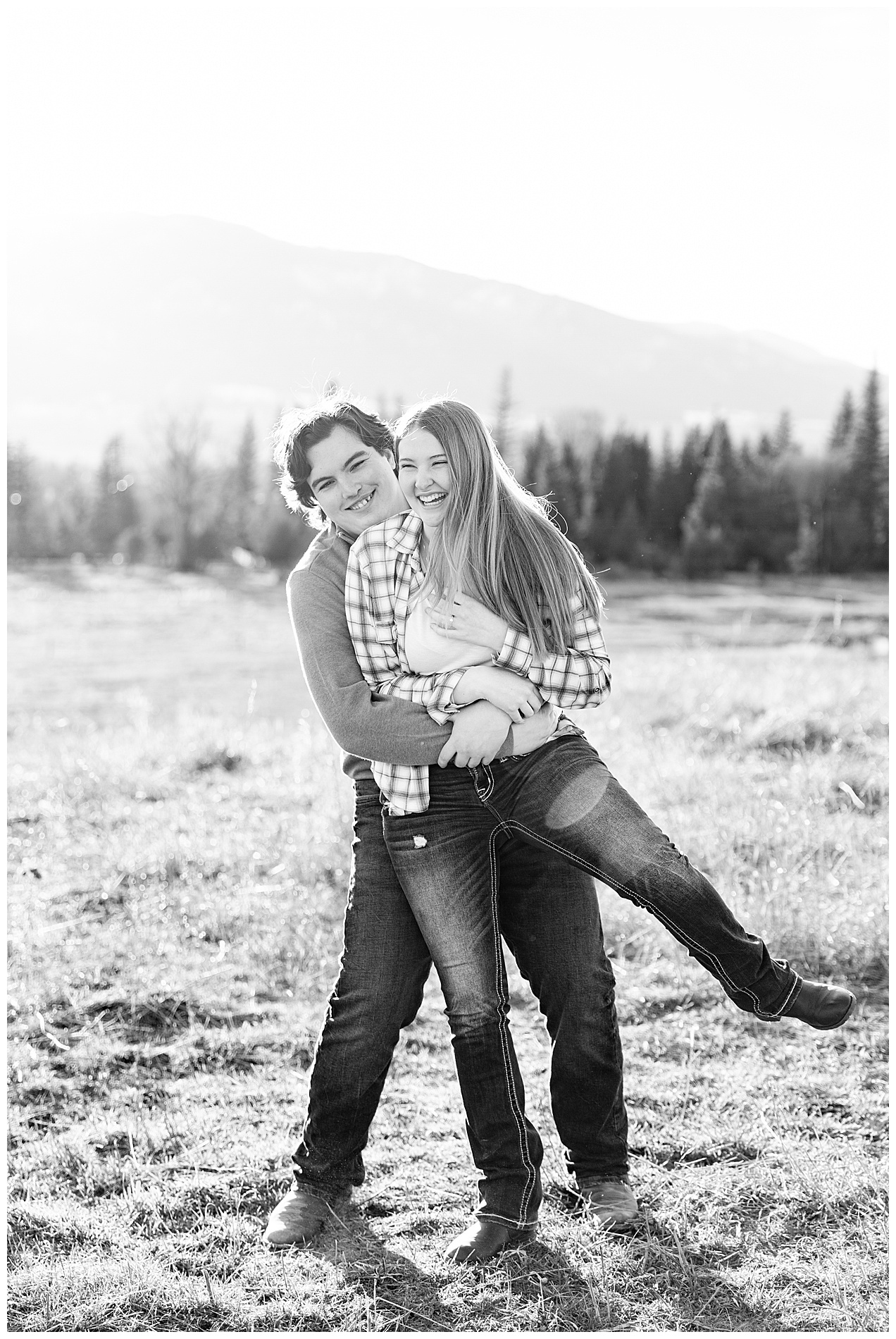 Engaged couple with the fiancé's arms around the waist of his bride-to-be while she laughs
