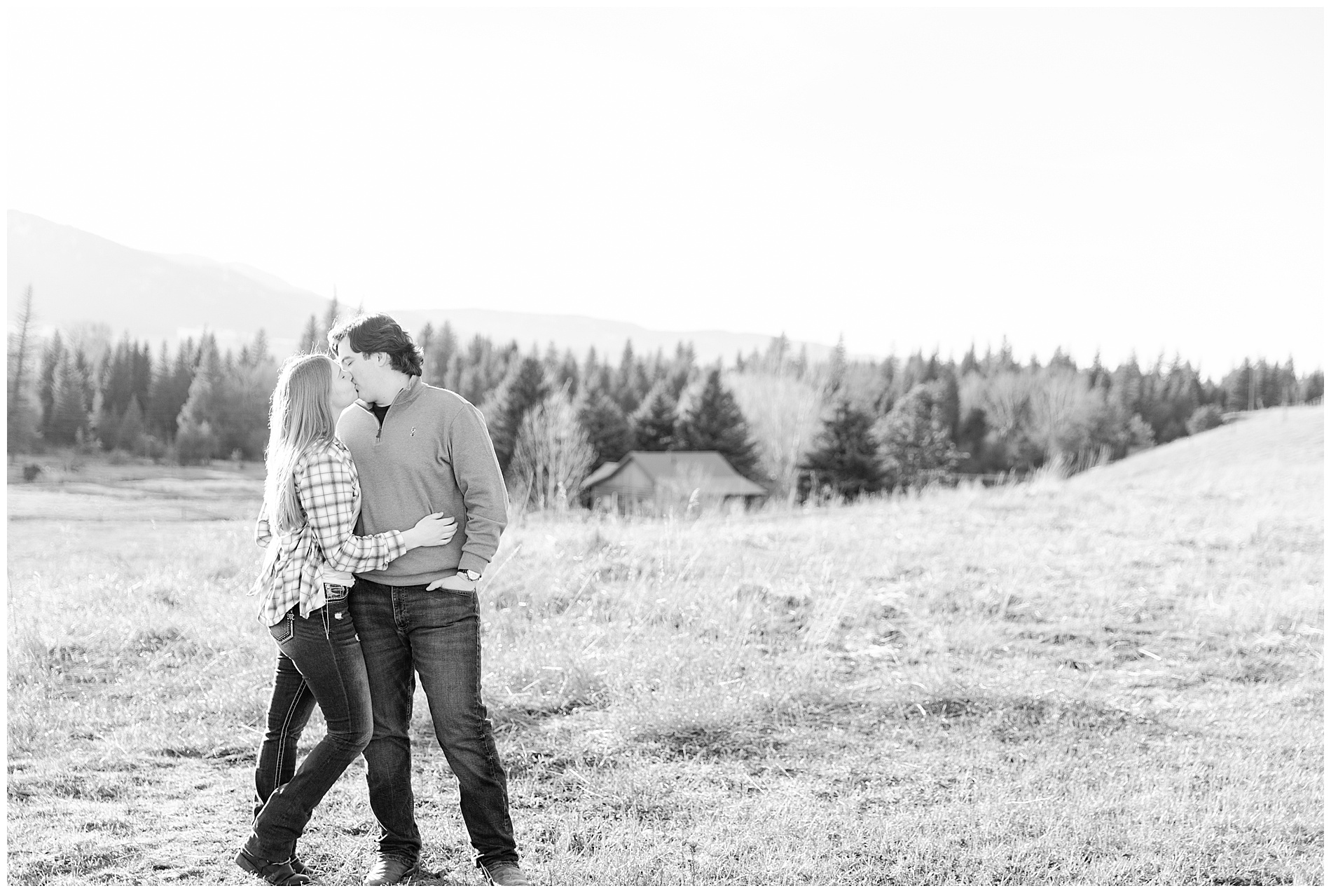 Engaged couple kissing, with a view of mountains and trees of Enterprise, Oregon
