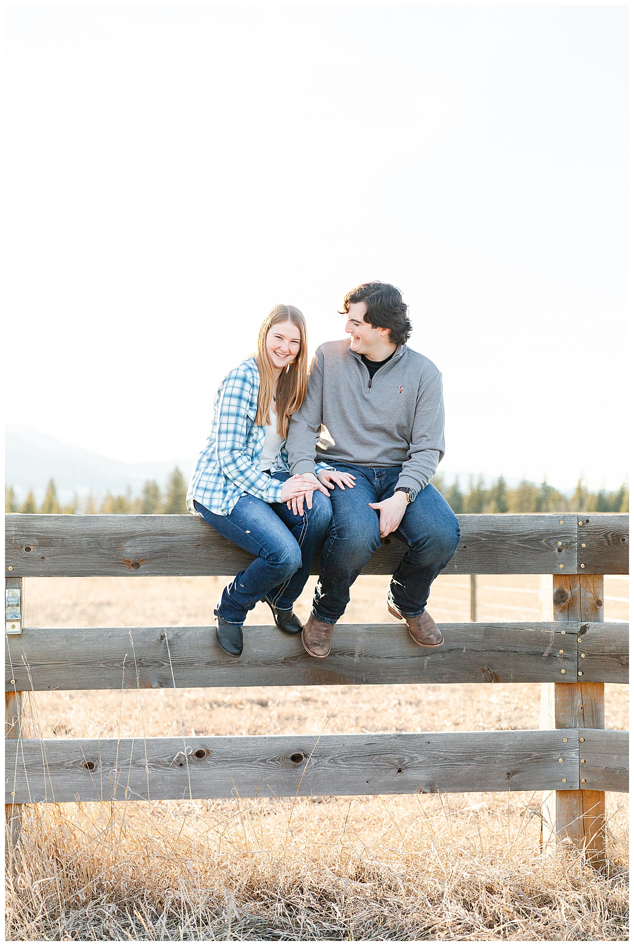 Engagement photo of a couple sitting on a wooden fence