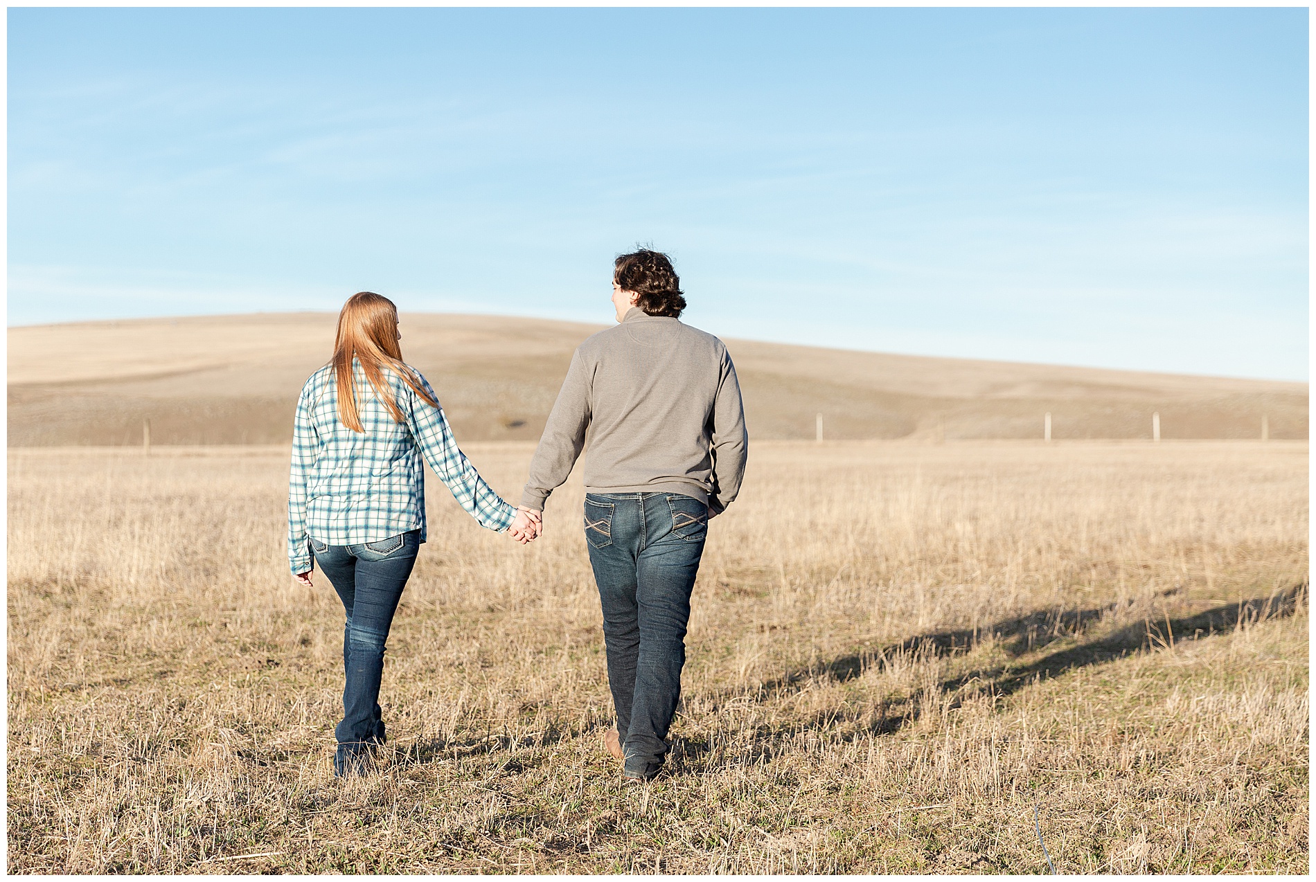 Couple walking away, holding hands, in an open field near Enterprise, Oregon