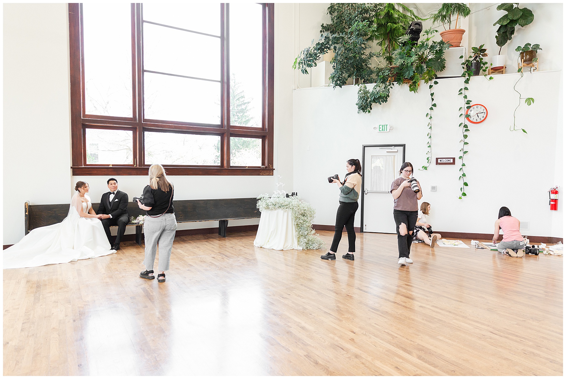 One photographer directs the couple for portraits while the other photographers photograph the champagne tower and wedding invitations