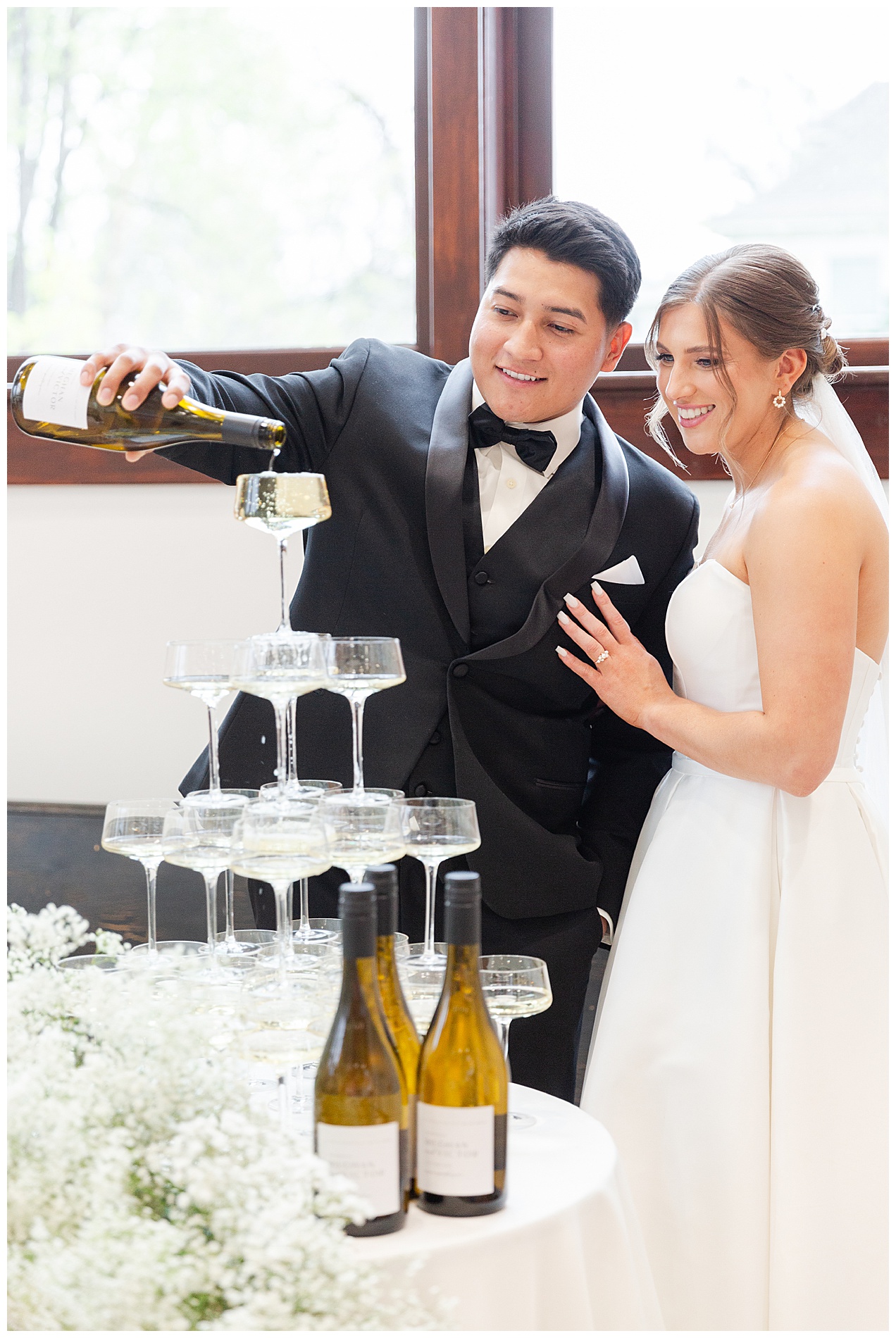 The couple smile as champagne trickles over the rim of the top glass and down into the other glasses below it