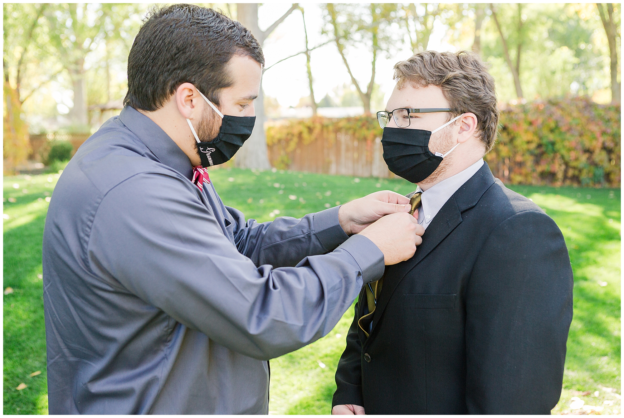 A groomsman straightens another groomsman's necktie