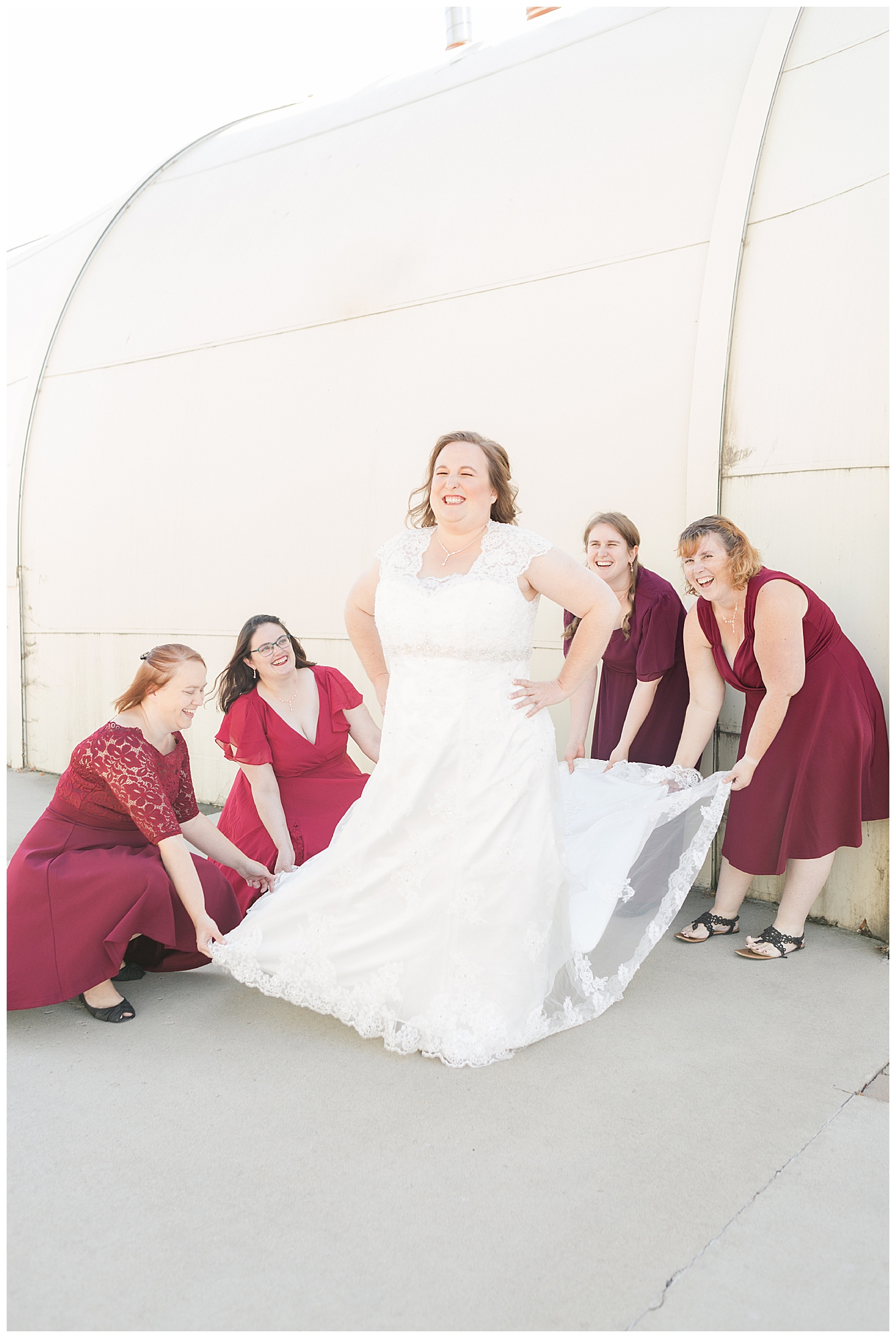 Bridesmaids laugh as they fluff out the bride's train