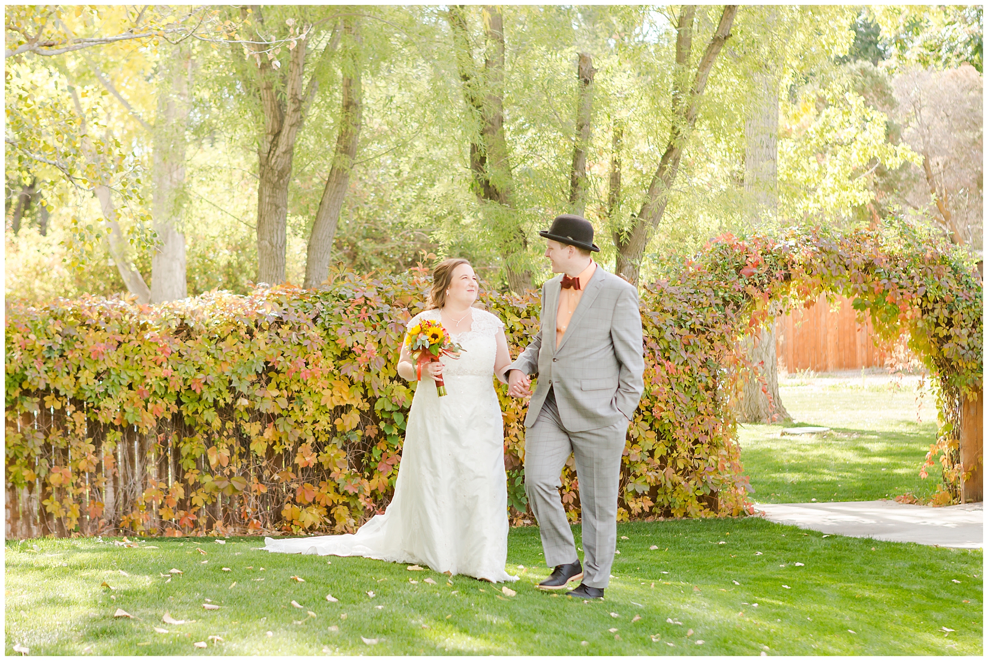 The bride and groom walking hand in hand; behind them is a beautiful vine-covered archway