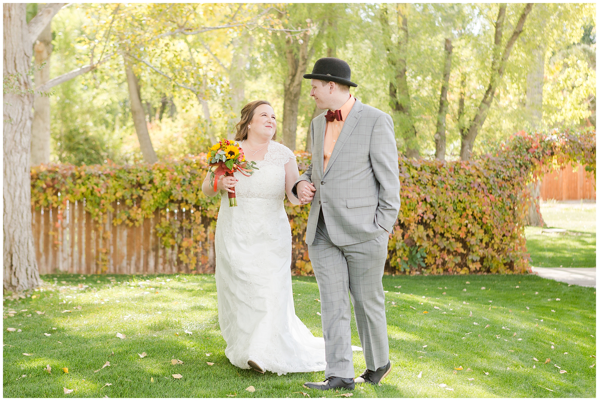 Bride and groom walking together outdoors with autumn colored foliage around them