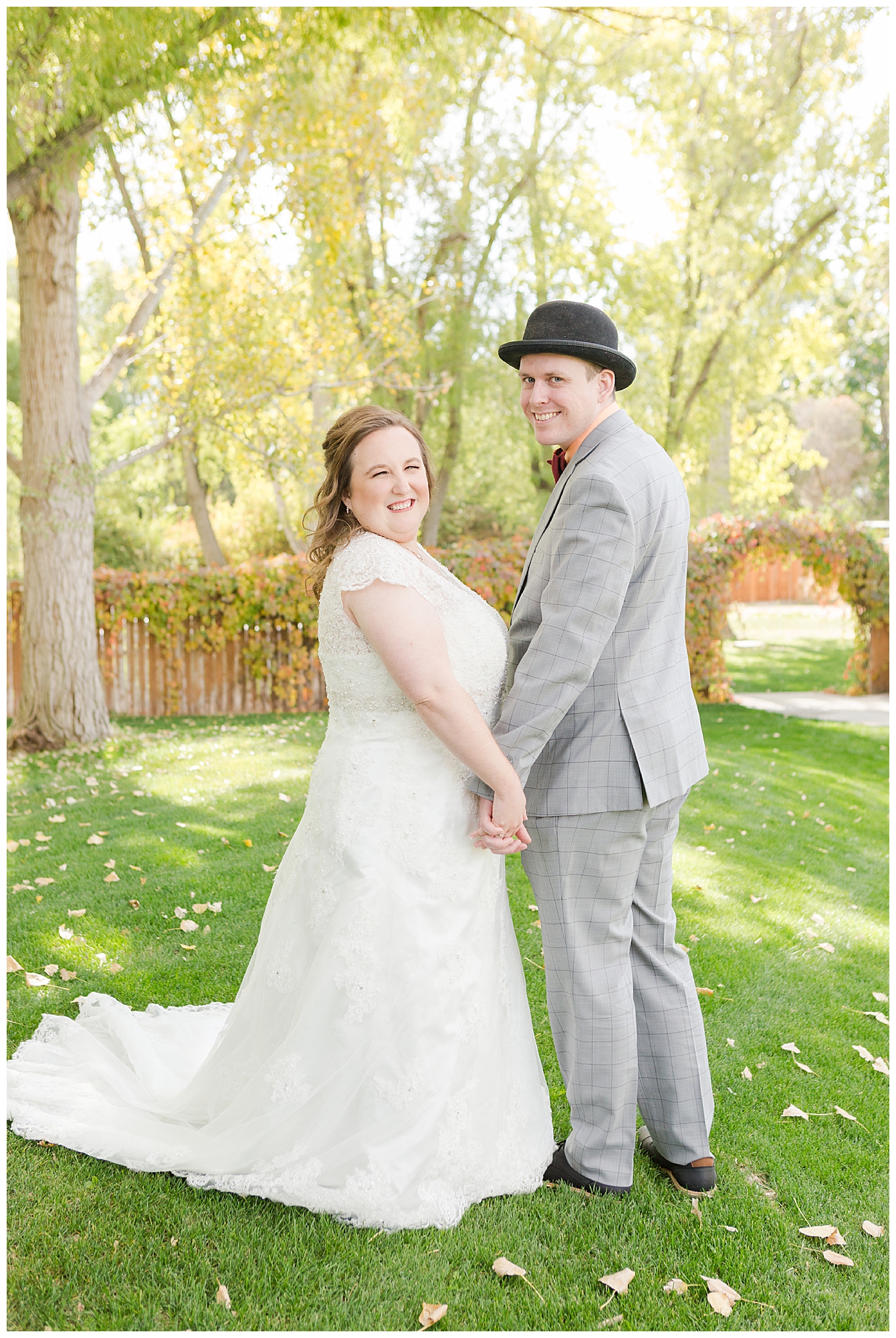 Bride and groom holding hands with beautiful autumn-colored vines and leaves in the background