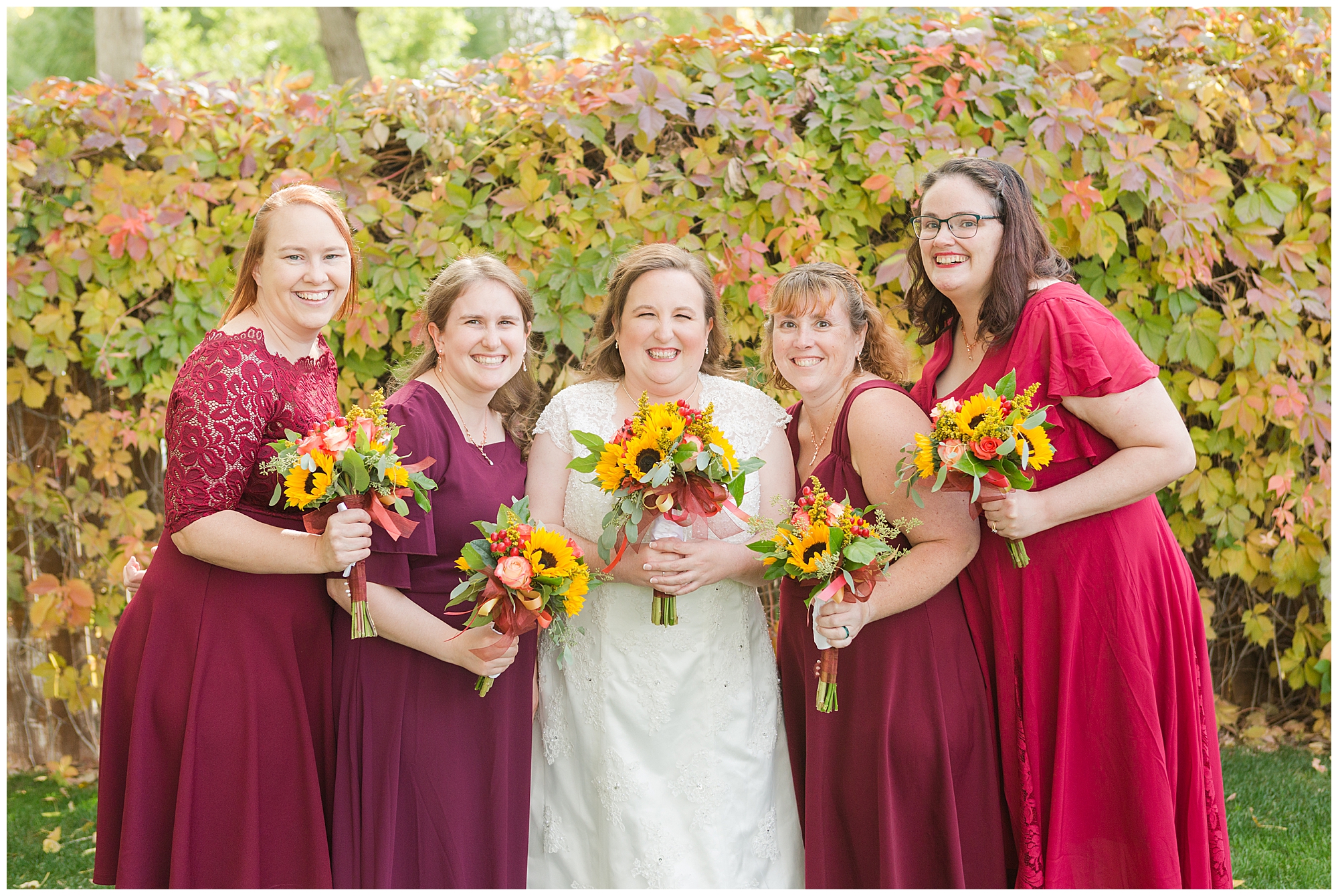 A bride with her four bridesmaids, all wearing different shades of burgundy, at a fall wedding in Nampa, Idaho