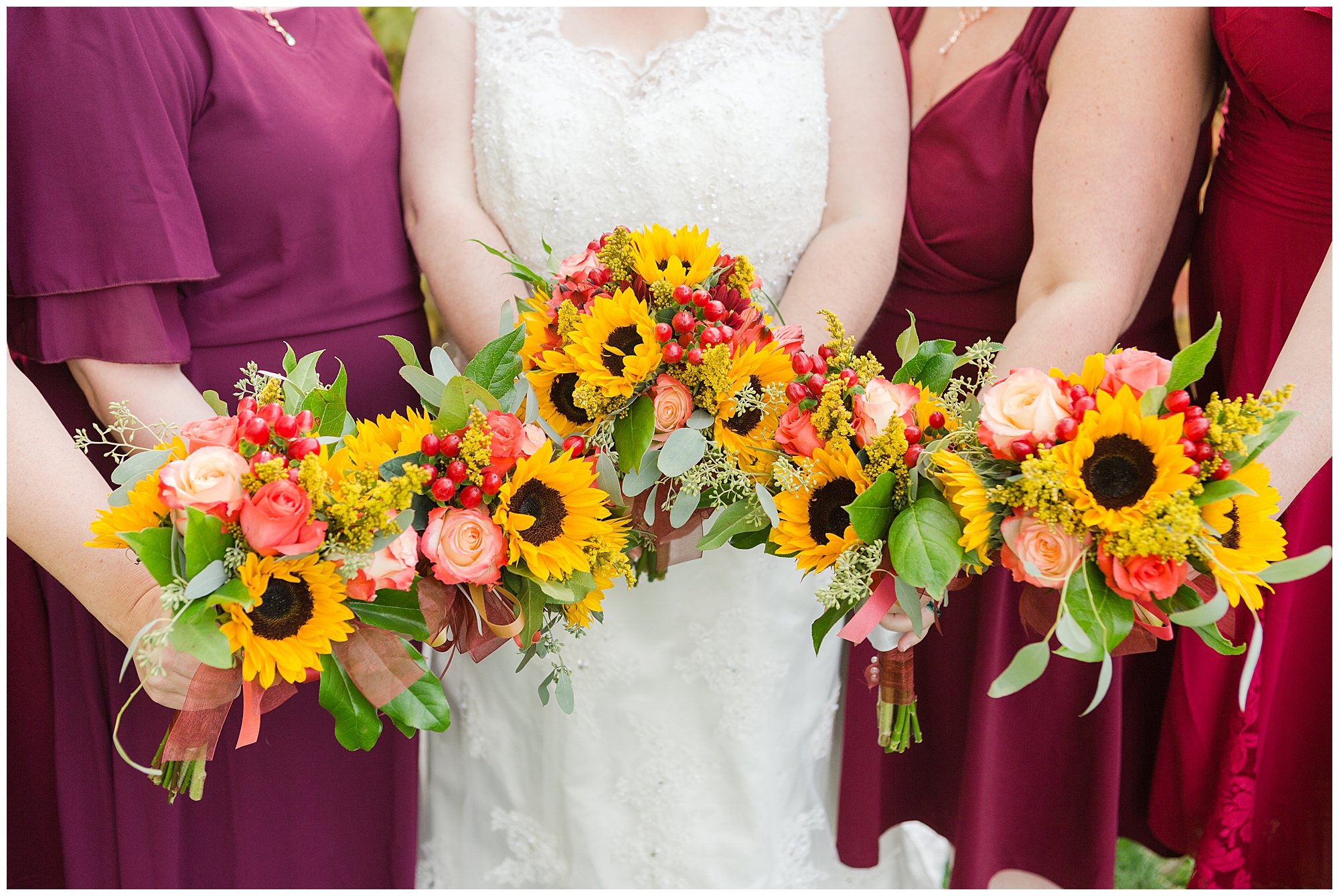 The bridesmaids and bride holding their rose, eucalyptus, and sunflower bouquets in a line