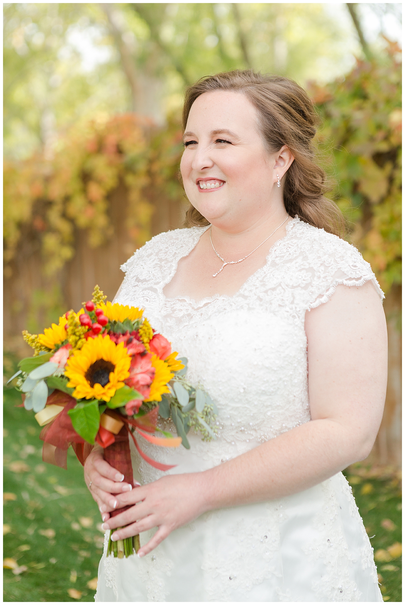 Portrait of the bride, holding her bouquet of sunflowers, with fall colors in the background