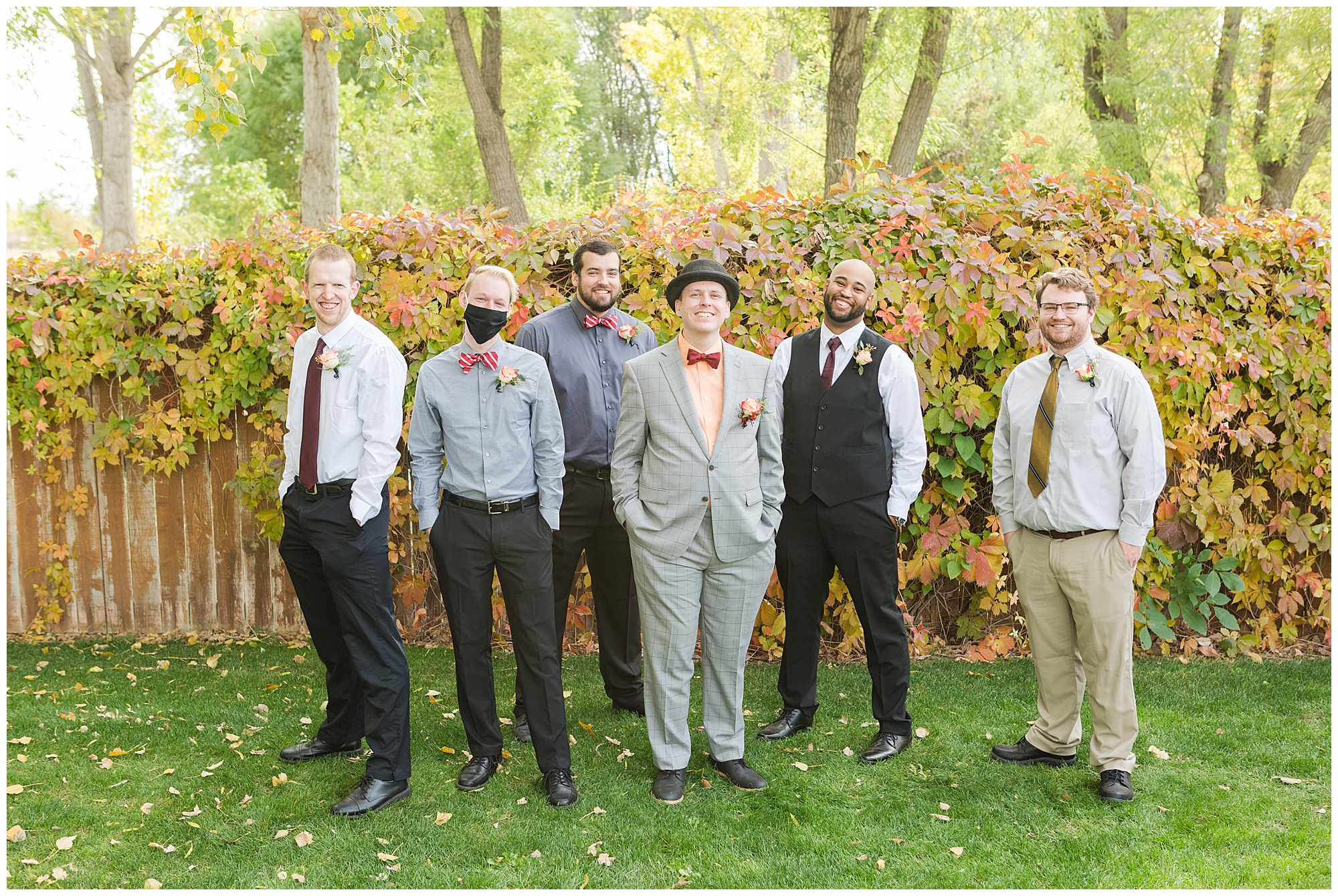 Groomsmen in mismatched autumn colors smile at the camera