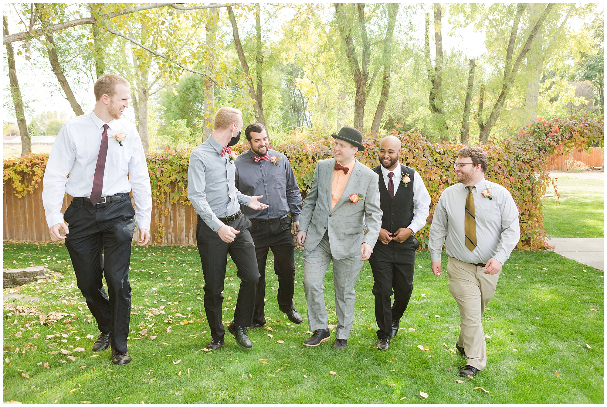 Groomsmen in mismatched fall colors walk and laugh together at Calvary Chapel in Nampa Idaho