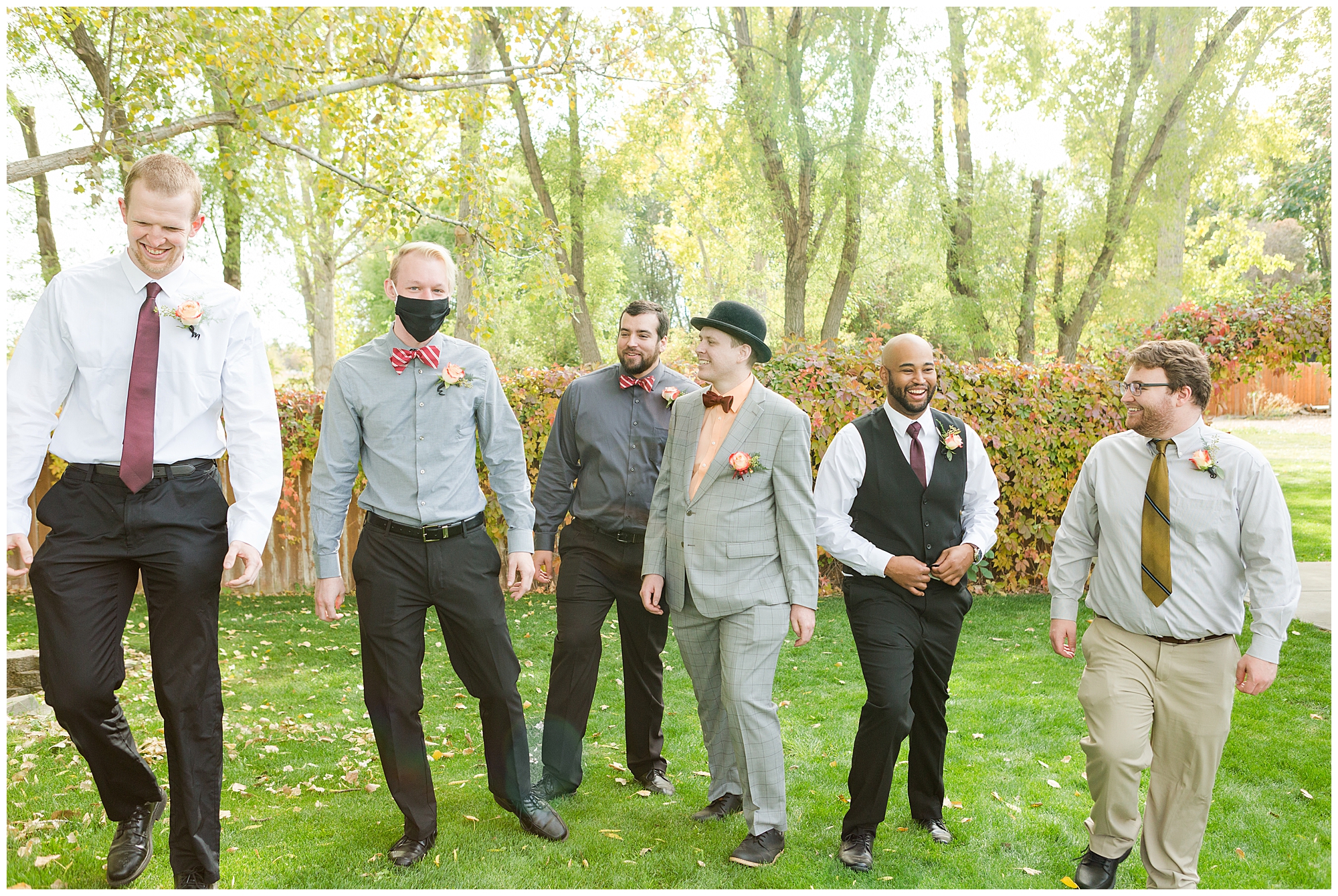 Groomsmen in mismatched fall colors walk and laugh together