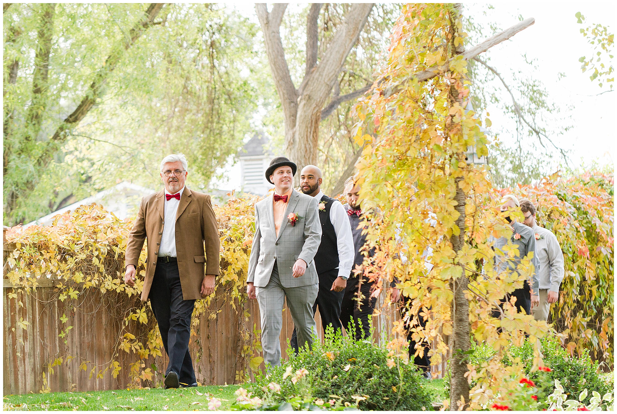 The officiant, groom, and groomsmen walk past golden foliage as they enter the amphitheater