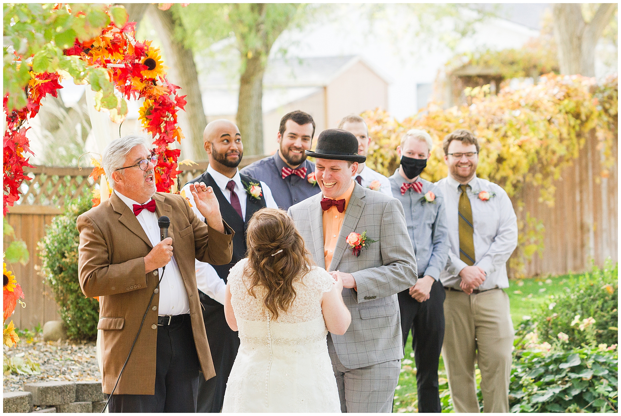 The groom and groomsmen laugh at the officiant's joke during the wedding ceremony