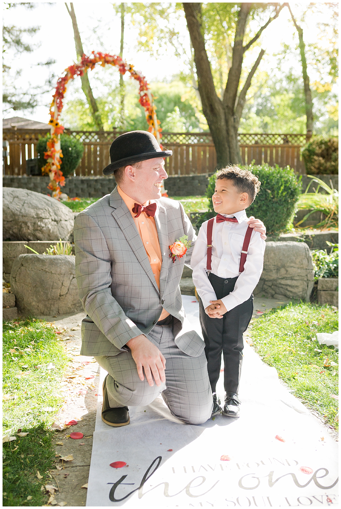 Groom in a top hat posing for a picture with the ring bearer