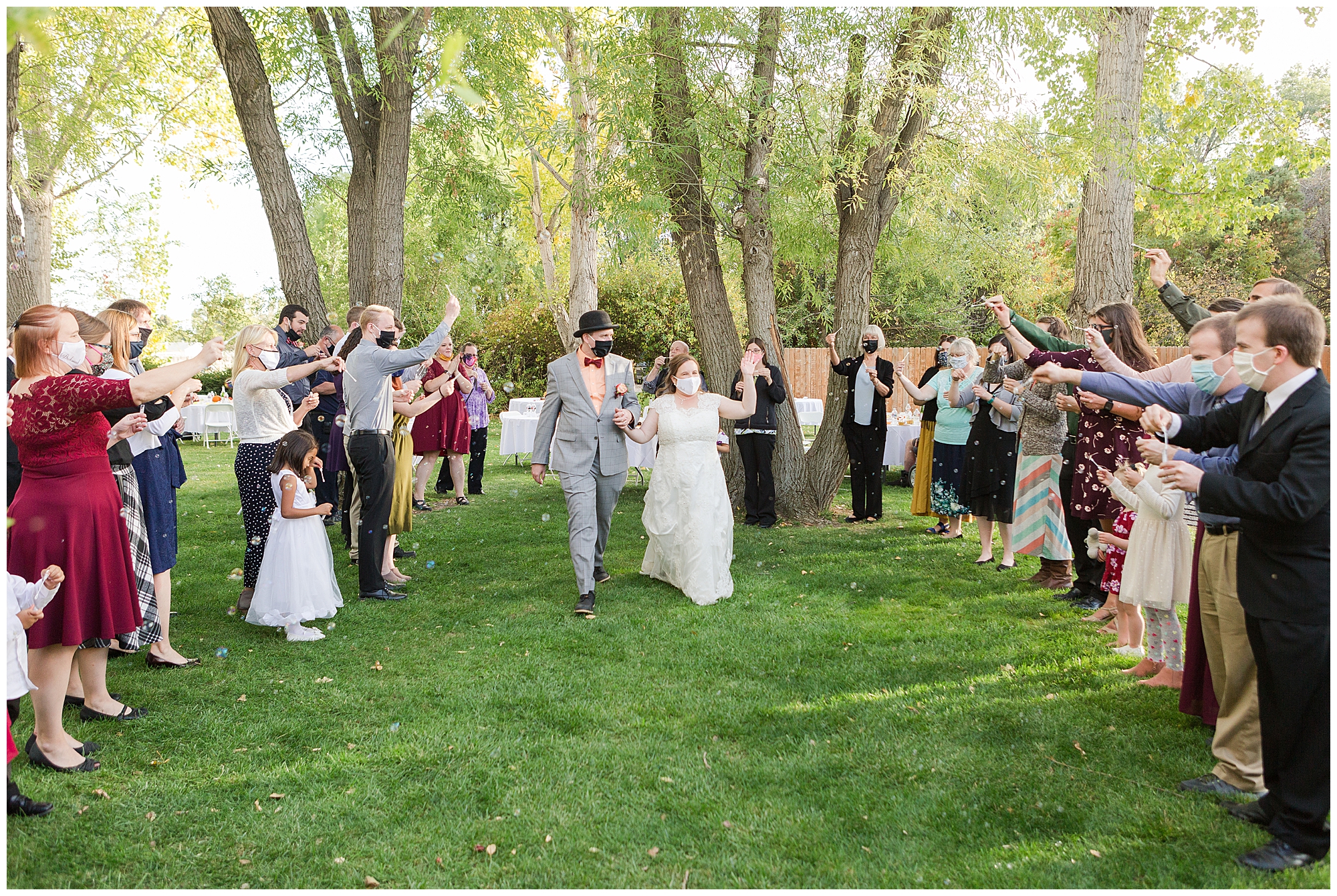 Bride and groom leaving their reception while guests blow bubbles