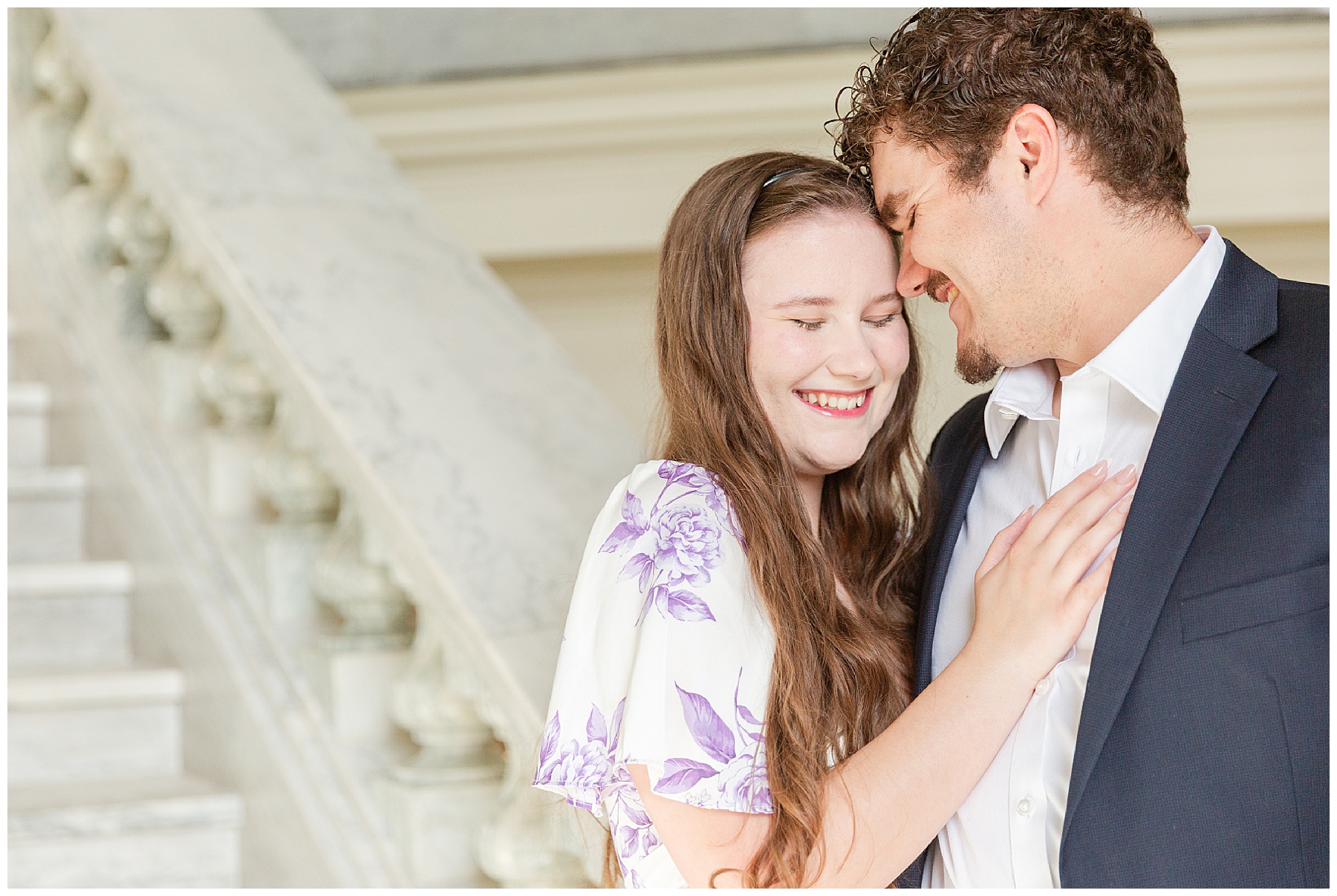 A close moment between the engaged couple near a marble staircase