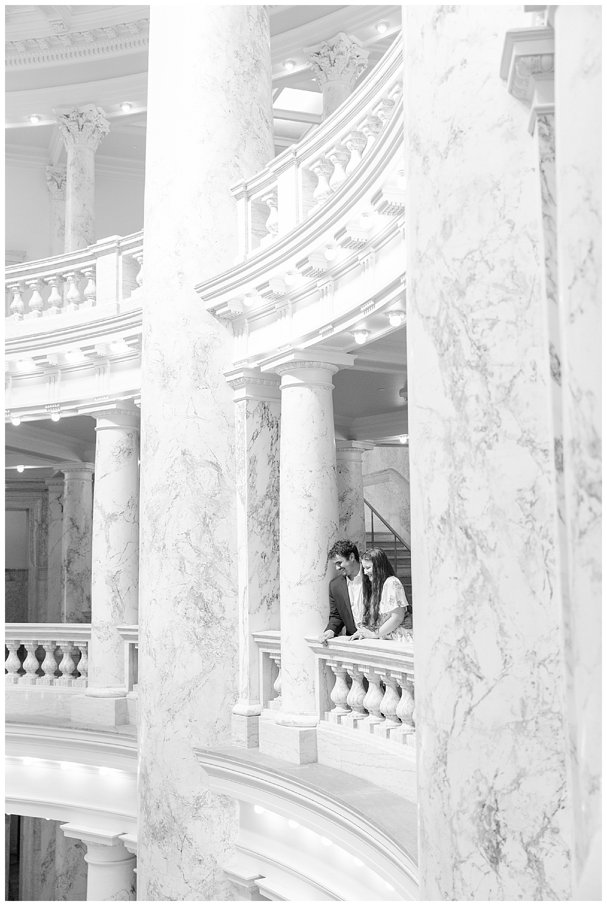 The couple looks down over a balcony on the third floor of the Idaho State Capitol, where a spontaneous wedding is taking place