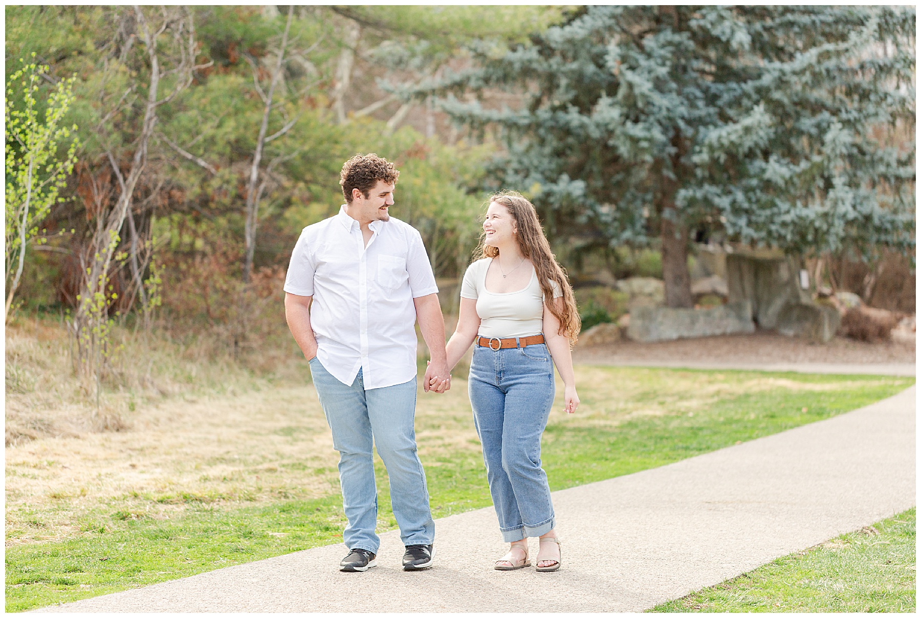 Portrait of an engaged couple walking along a path in the park in spring