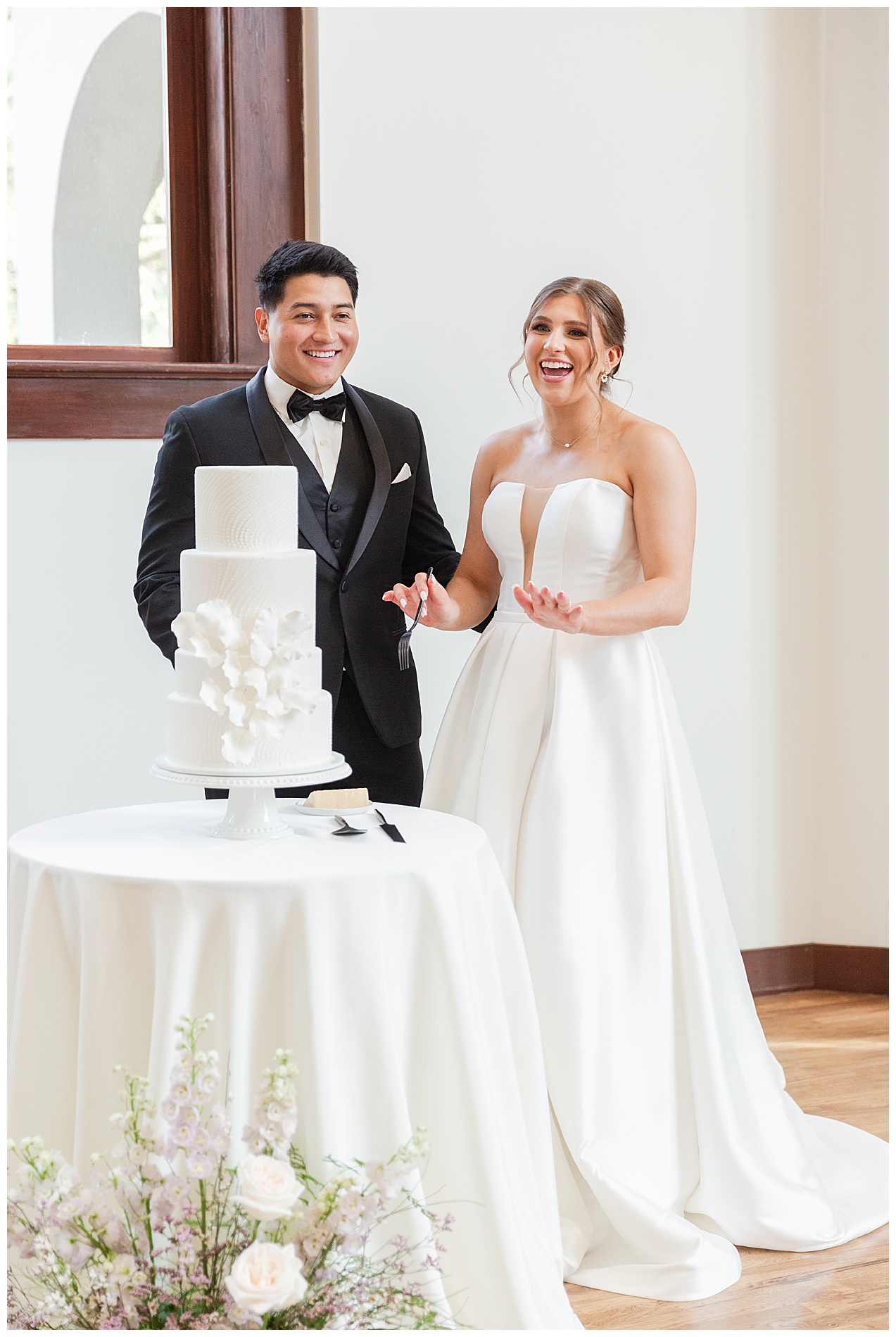 The groom and bride laugh before taking their first bite of the wedding cake