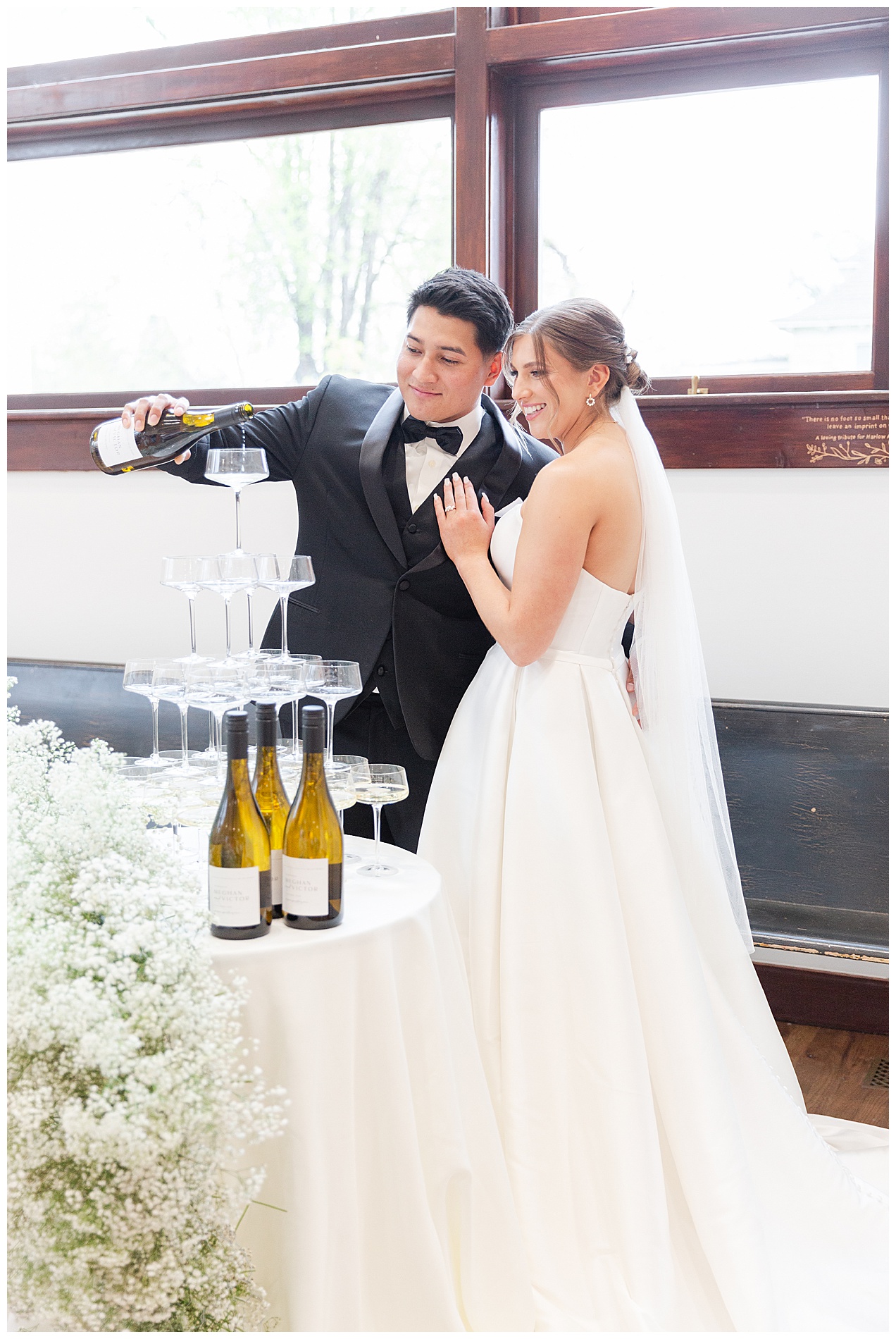 The groom and bride begin to pour champagne into the top glass