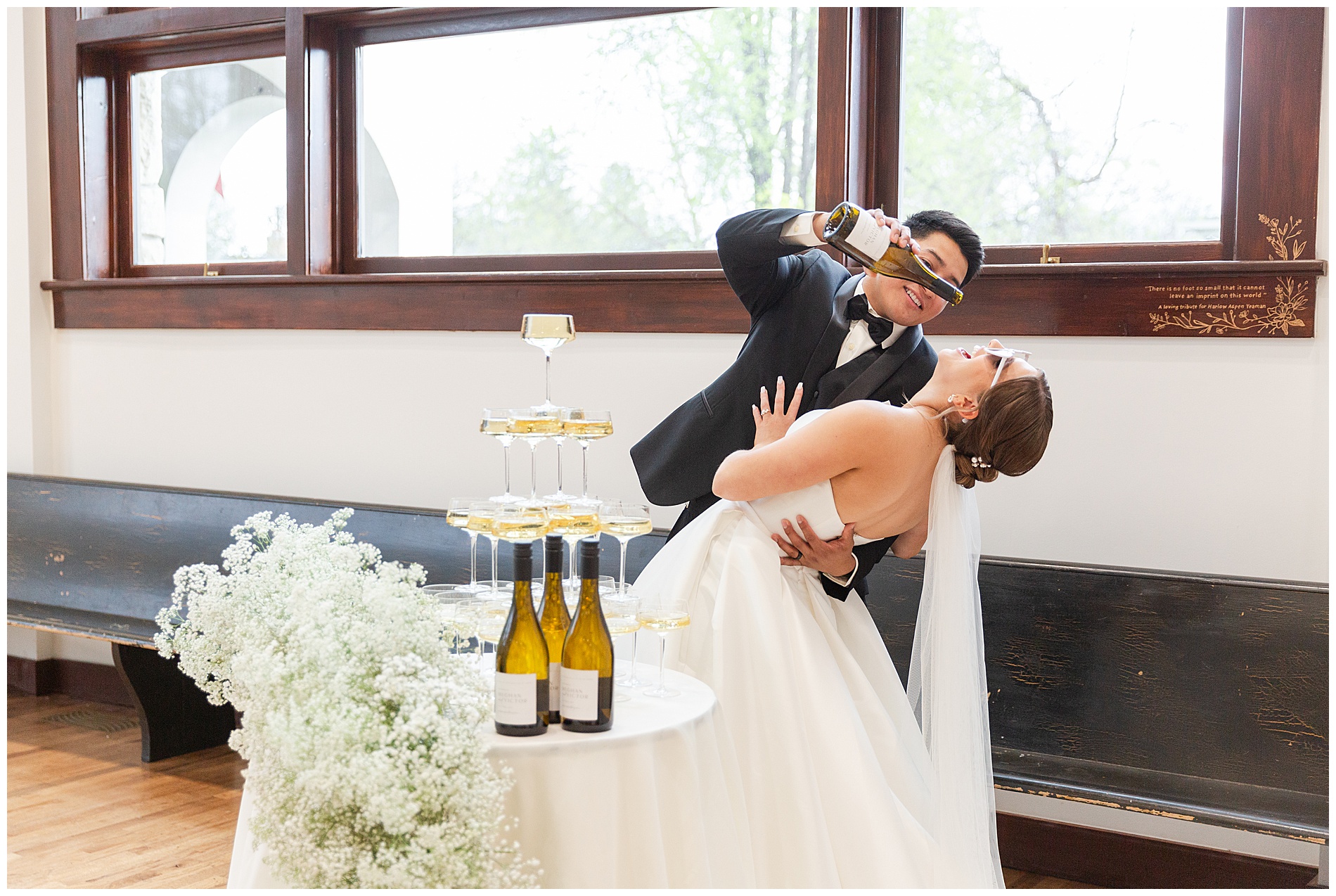 The groom dips the bride backward as if he's pouring the last of the champagne into her open mouth