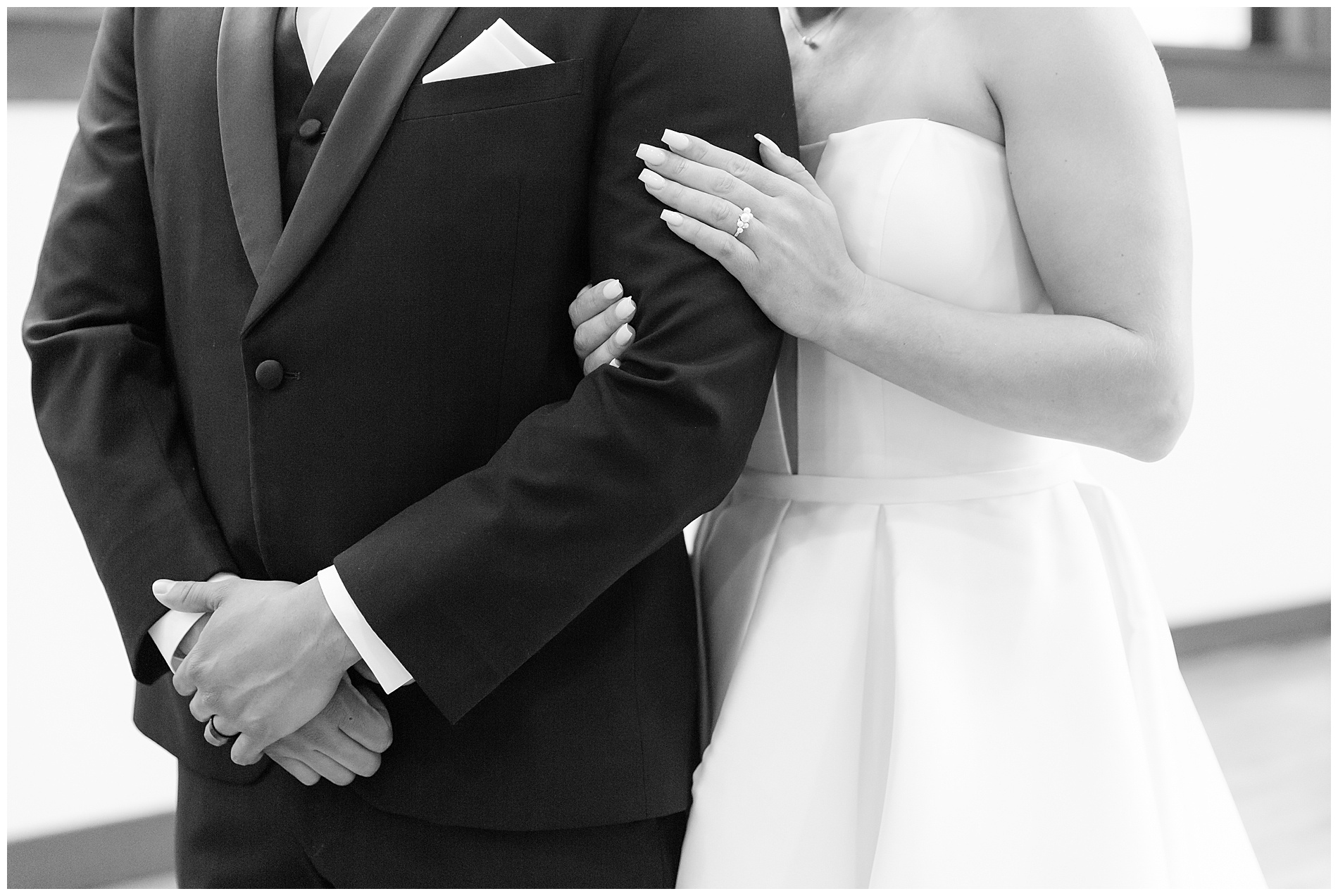 Closeup on the bride's hands wrapped around the groom's arm