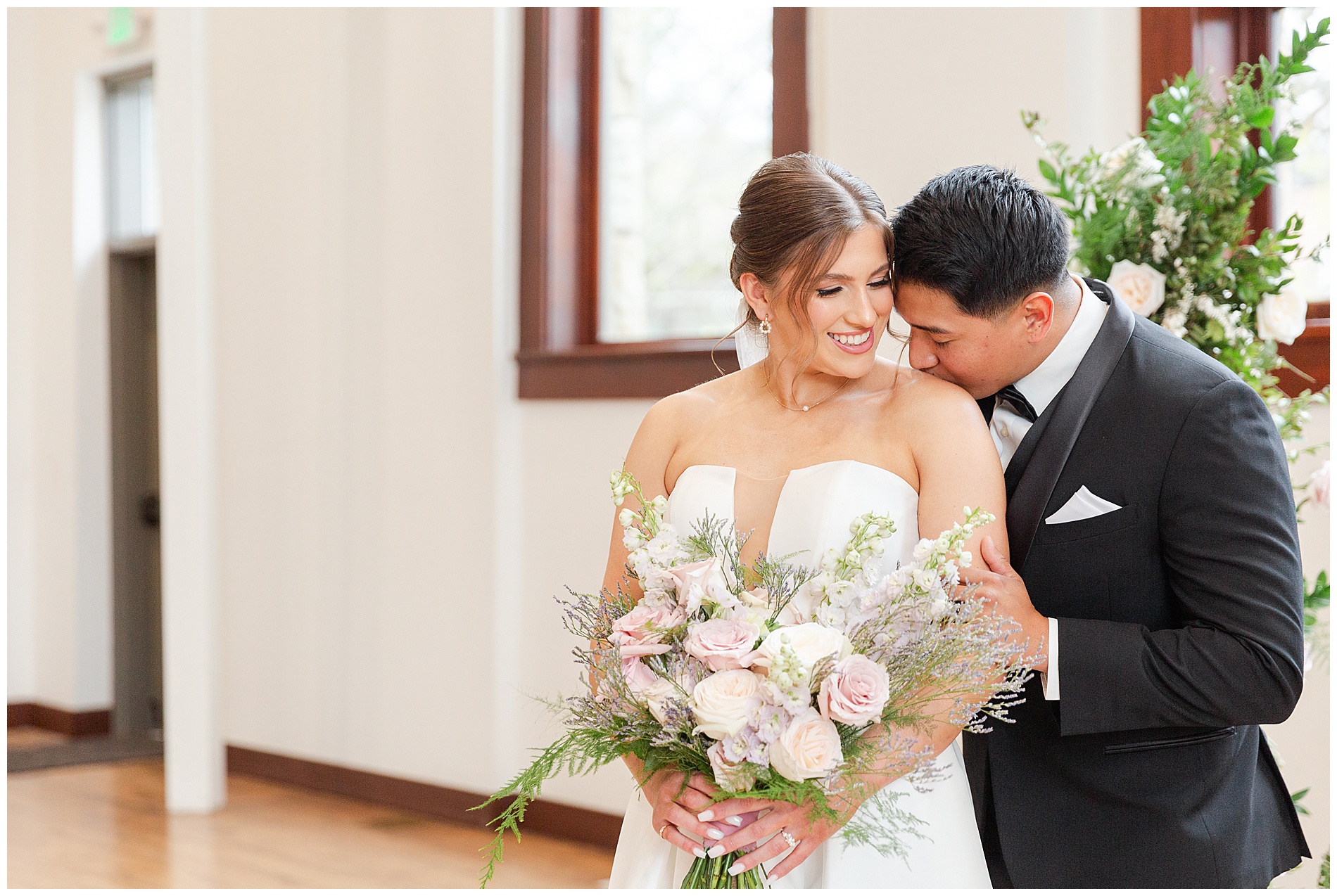 The groom kisses the bride on her shoulder